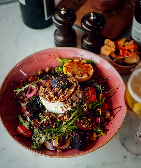 Sallad med vit ost, rödbetor och syltad rödlök i en rosa skål